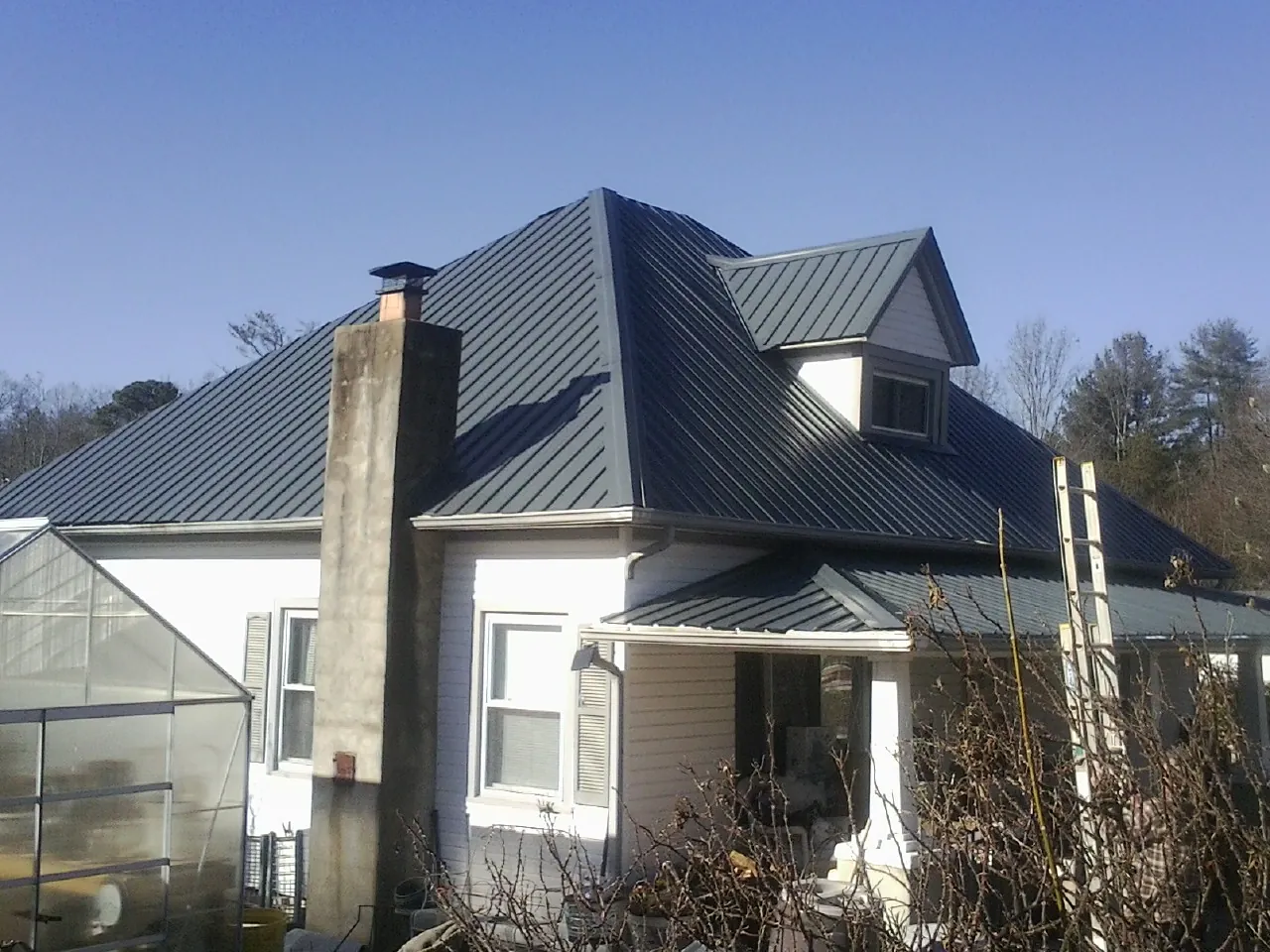 Dark blue standing seam metal roof on a white farmhouse with dormer — Slate & Tile Roof Repair by Roofing Brothers in Los Angeles