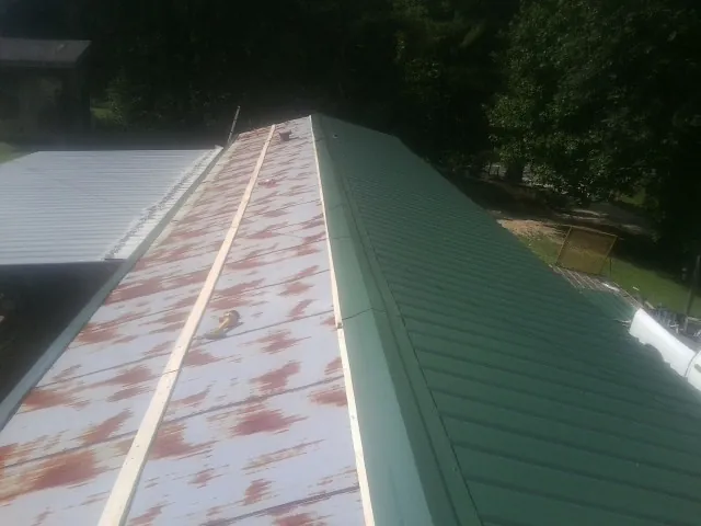 Old rusted panels beside newly installed green metal roofing — Wind Damage Roof Repair by Roofing Brothers in Los Angeles