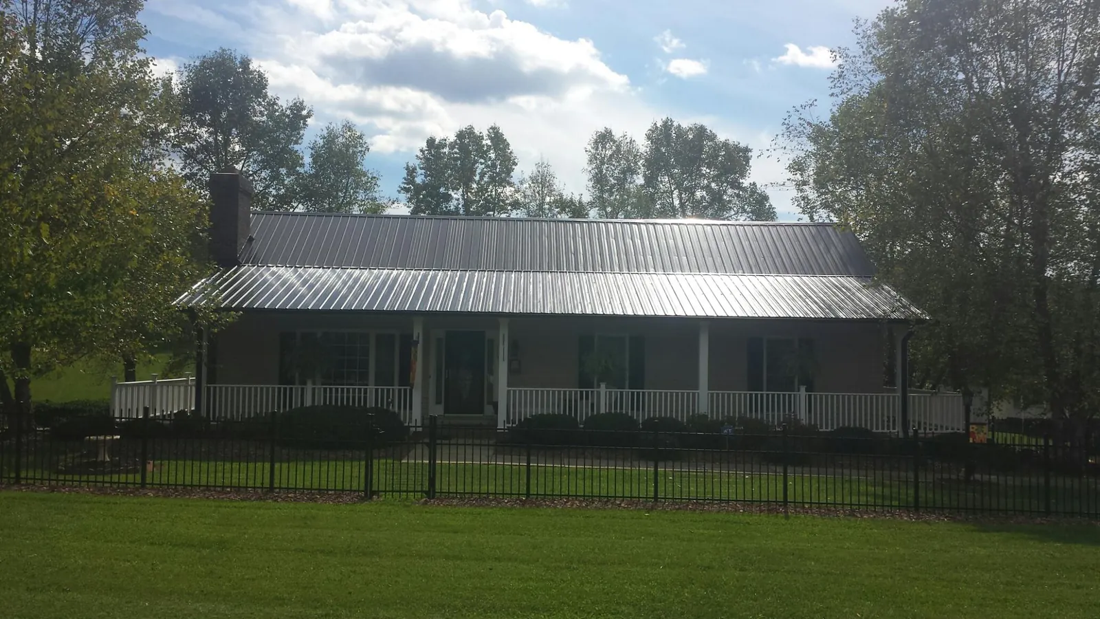 Gray metal roof on a brick ranch with a full width front porch — Gutter Guard Installation work by our crew in Los Angeles