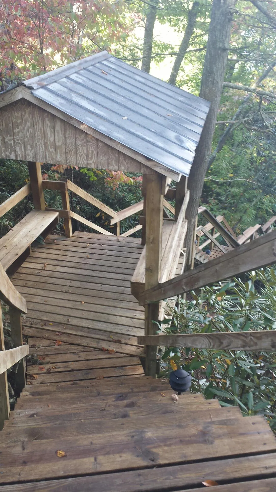 Metal roofed shelter over wooden steps on a wooded walkway — Skylight Repair & Installation work by our crew in Los Angeles