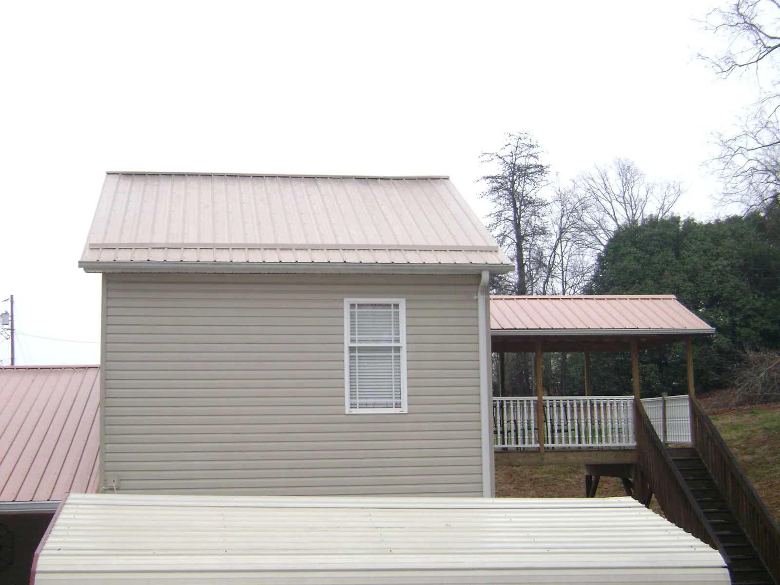 Tan metal roofs on a two story addition and attached porch, from a Roof Replacement job in Los Angeles